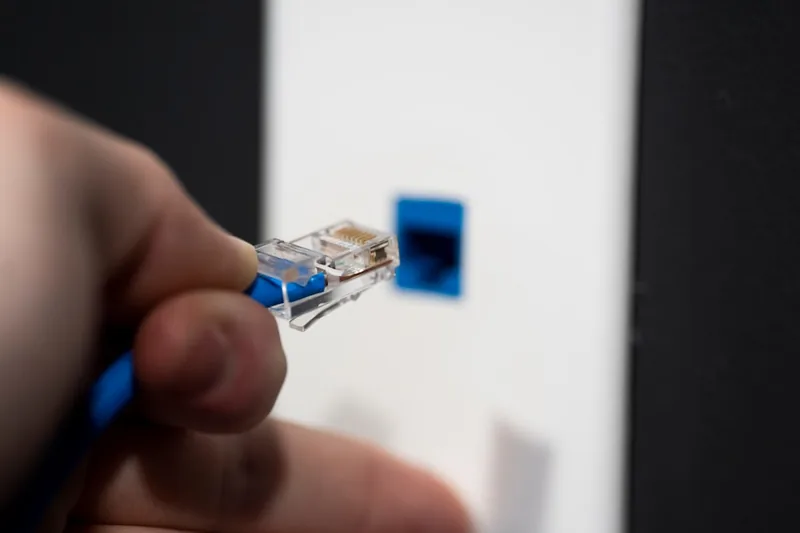 Eine Person verbindet ein Netzwerkkabel mit einer Hardware-Firewall, um das Gerät einzurichten.