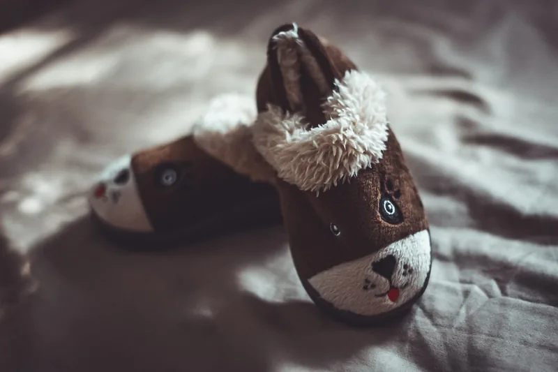 Ein Kind spielt auf dem Boden, während es bequeme Kinder-Hausschuhe trägt, die Schutz und Wärme bieten.