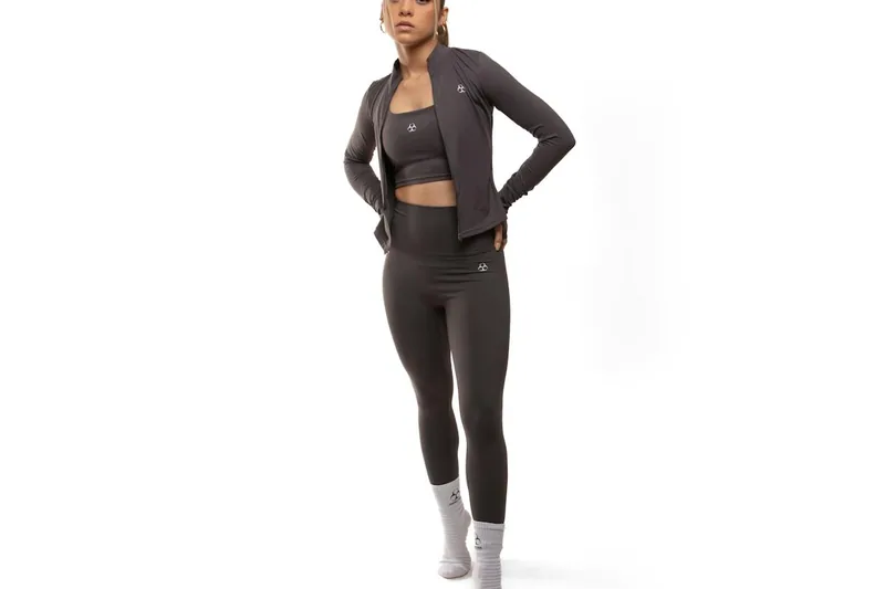 Eine Frau in schwarzen High Waist Leggings macht eine Yoga-Pose, zeigt Flexibilität und Tragekomfort im Einsatz.