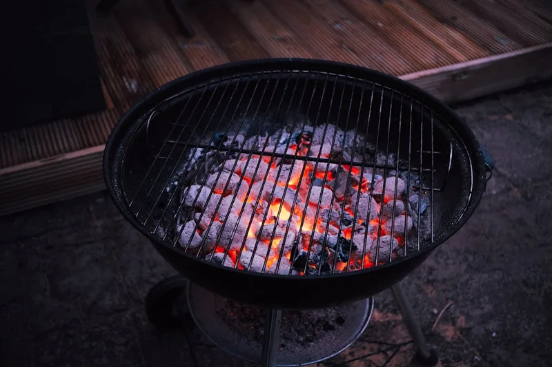 Atmosphärische Gartenparty mit Freunden, im Hintergrund ist ein Holzkohlegrill in Aktion zu sehen.