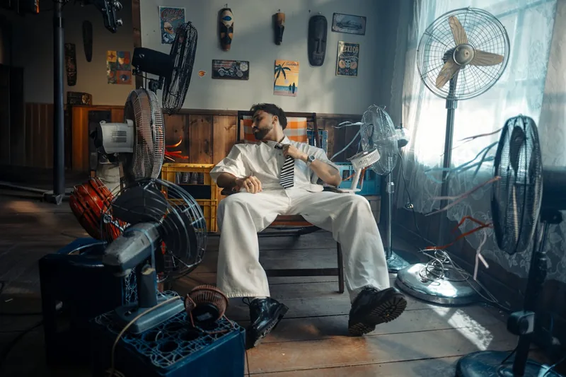 Eine Person verstellt einen kompakten Tischventilator in einem gemütlichen Wohnzimmer für optimale Luftzirkulation.