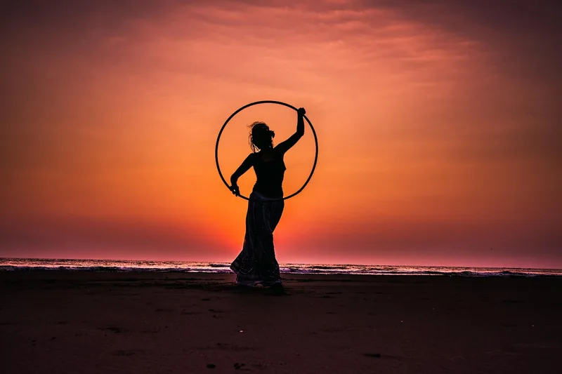 Eine Person trainiert konzentriert mit einem Hula-Hoop-Reifen im Freien, symbolisiert Fitness und Spaß.