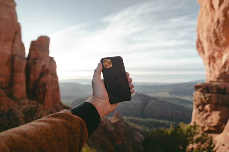 Hand hält iPhone 11 mit Outdoor-Hülle während einer Wanderung.