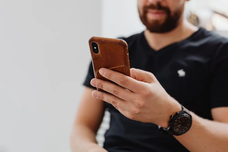 Eine Person hält ein iPhone 12 in einer stilvollen Lederhülle in der Hand, bereit zur Benutzung.