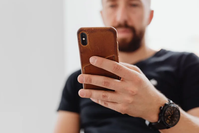 iPhone 12 Lederhülle auf einem modernen Schreibtisch, umgeben von Notizbuch und Stift.
