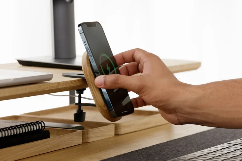 Eine Hand hält ein iPhone 12 Pro, während das MagSafe-Ladegerät kabellos magnetisch andockt.