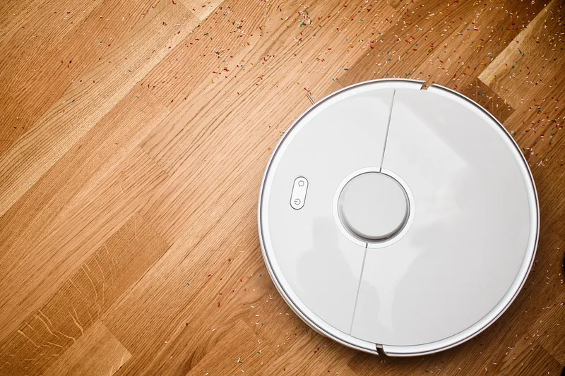 Ein moderner, runder Staubsaugroboter von oben betrachtet, freigestellt auf weißem Hintergrund.