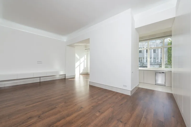 Ein makelloses, modernes Wohnzimmer mit sauberem Parkettboden und minimalistischer Einrichtung.