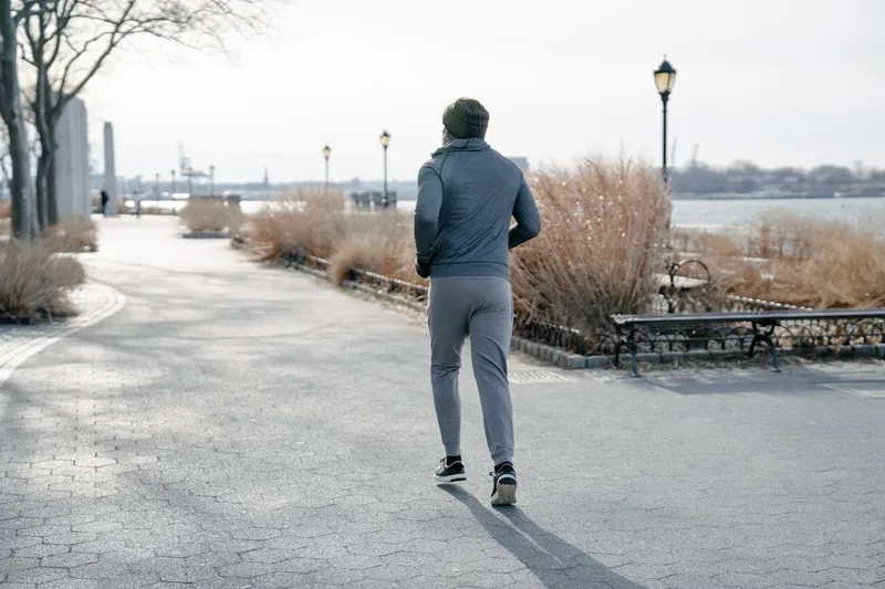 Ein Mann in schwarzer Herren-Jogginghose joggt im Park, Dynamik und Bewegungsfreiheit.