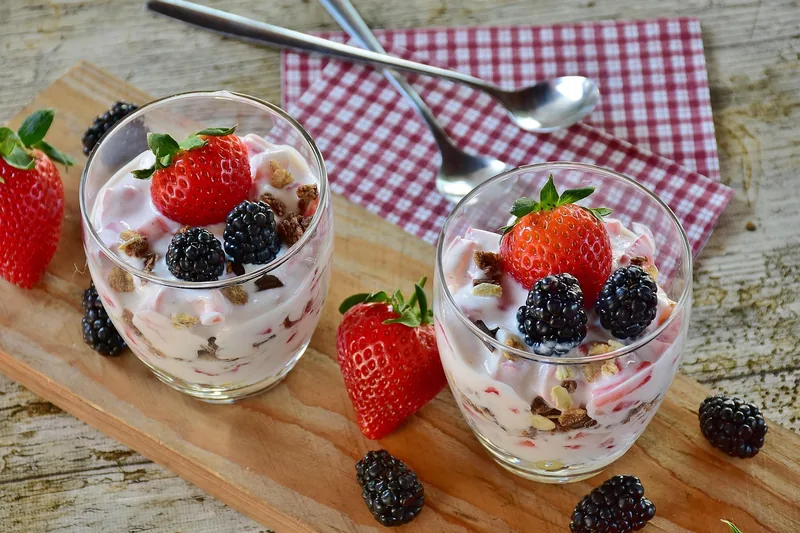 Eine Hand füllt Milch in einen Joghurtbereiter, um frischen, selbstgemachten Joghurt herzustellen.
