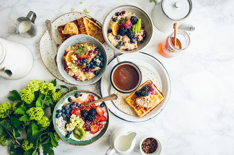 Ansprechender Frühstückstisch mit frisch zubereitetem Joghurt, Früchten und Müsli.