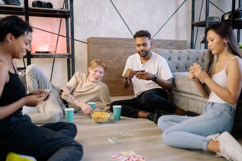 Freunde verbringen einen gemütlichen Abend beim Kartenspielen im Wohnzimmer.