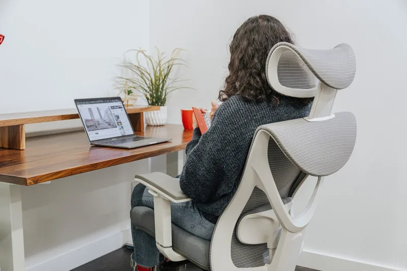 Ein aufgeräumter, ergonomischer Büroarbeitsplatz mit Stuhl und Keilkissen, strahlt Komfort aus.