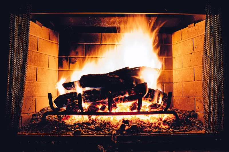 Ein gemütlicher, lodernder Kamin mit hell glühendem Feuer, das Wärme und Behaglichkeit ausstrahlt.