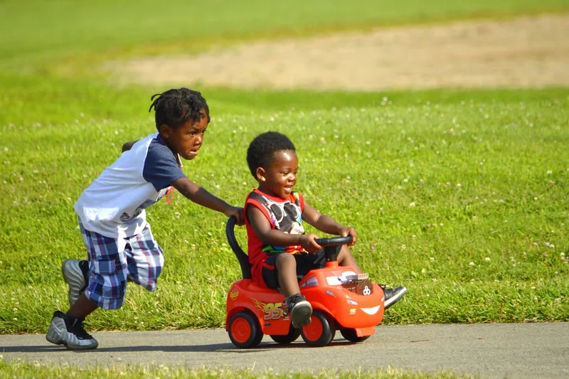 Kind fährt mit einem Kinder-Elektroauto auf einer Terrasse.