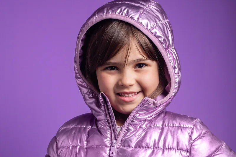 Eine farbenfrohe Kinder-Winterjacke, freigestellt vor hellem Hintergrund, präsentiert das Produkt.