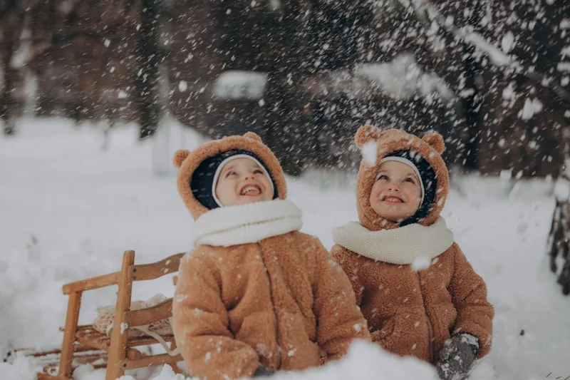 Winterlandschaft mit Kindern beim Rodeln, bereit für jedes Abenteuer mit der richtigen Kinder-Winterjacke.
