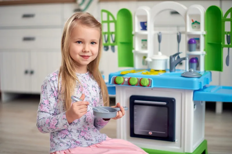 Ein Kind spielt an einer Kinderküche, ahmt spielerisch das Kochen nach und entwickelt motorische Fähigkeiten.