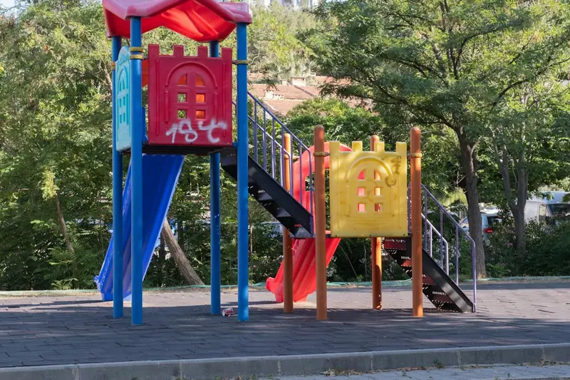 Ein bunter Spielturm mit integrierter Kinderrutsche in einem sonnigen Garten, als Teil einer Spiellandschaft.