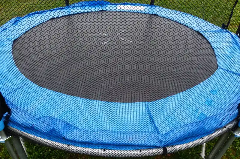 Detailansicht des robusten Sicherheitsnetzes und der gepolsterten Federn eines Kindertrampolins.