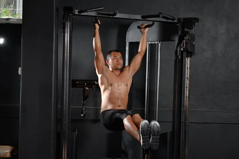 Ein sportlicher Mann führt Klimmzüge an einer stabilen Klimmzugstange in seinem Heim-Fitnessraum aus.
