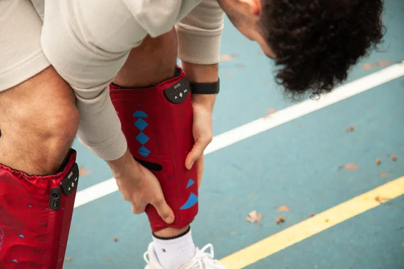 Eine Person legt eine Kniebandage präzise an das Knie an, um optimalen Halt zu gewährleisten.