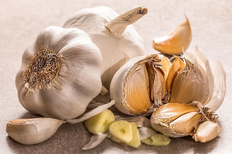 Eine appetitliche Küchenszene mit frischem Knoblauch, Kräutern und anderen Kochzutaten auf einer Arbeitsplatte.