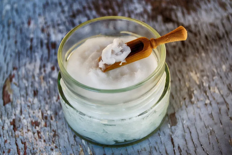 Ein geöffnetes Glas mit hochwertigem nativem Kokosöl, fest und bereit zur Verwendung in der Küche.