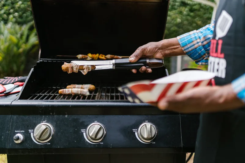 Eine Hand wendet Steak und Gemüse auf dem aktiven Kombigrill während einer Gartenparty.