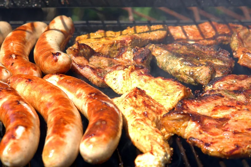 Eine entspannte Grillparty-Atmosphäre im sommerlichen Garten, mit leckerem Essen auf dem Tisch.