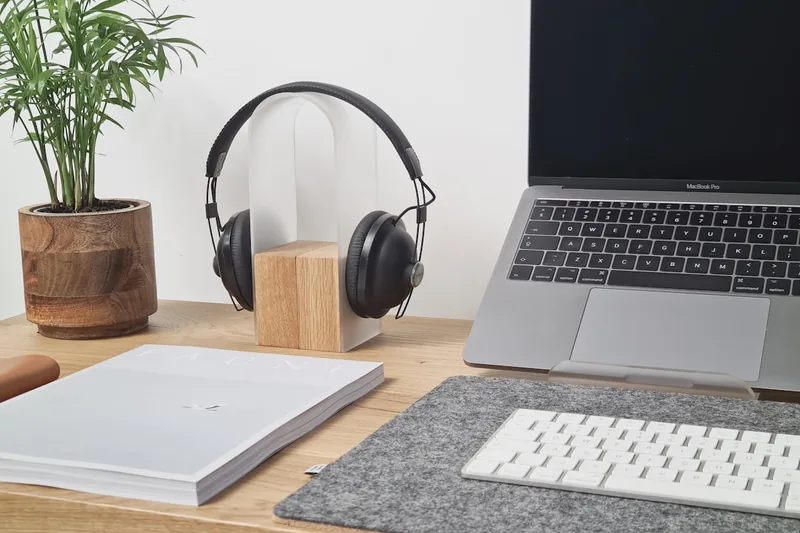 Kopfhörer liegen auf einem Schreibtisch in einem modernen, hellen Home-Office-Setting mit Pflanzen.