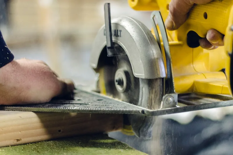 Eine Person bedient eine Handkreissäge, um ein Holzstück präzise zu schneiden, mit Fokus auf die Anwendung.