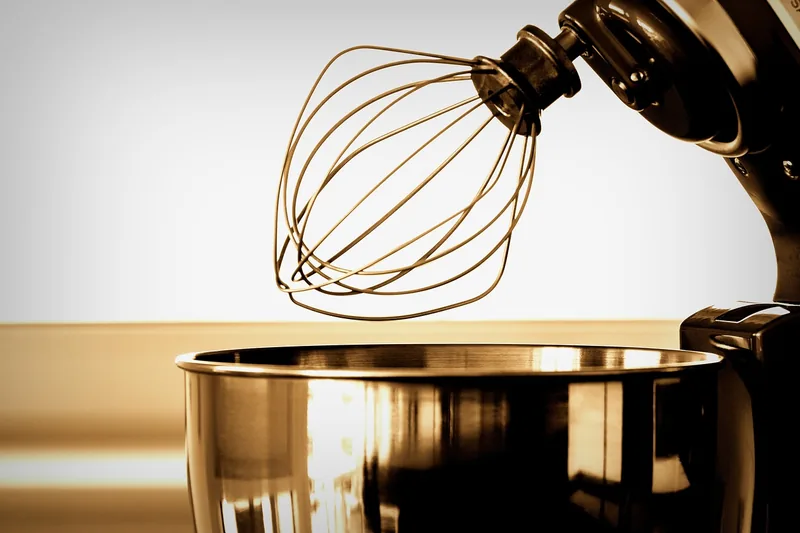 Nahaufnahme einer Küchenmaschine: Detail des glänzenden Metall-Rührbesens, Fokus auf Material und Verarbeitung.