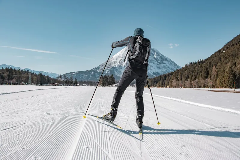 Ein Langläufer im Einsatz, nahaufnahme auf die Langlaufhose bei dynamischer Bewegung im Schnee.
