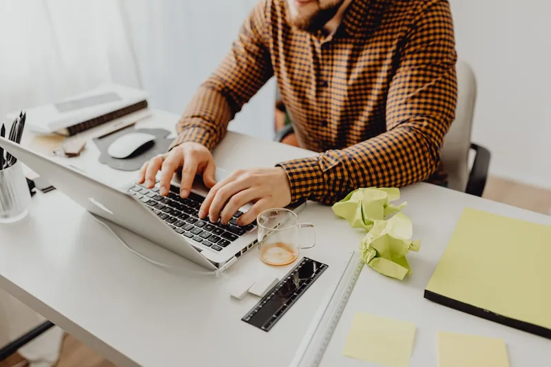 Person arbeitet fokussiert an einem geöffneten 17-Zoll-Laptop in einem modernen Home-Office-Setup.