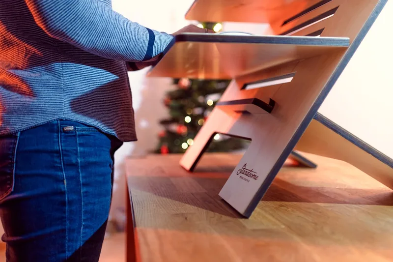 Eine Person arbeitet am Schreibtisch mit Laptop auf einem Laptop-Ständer, verbesserte Ergonomie sichtbar.