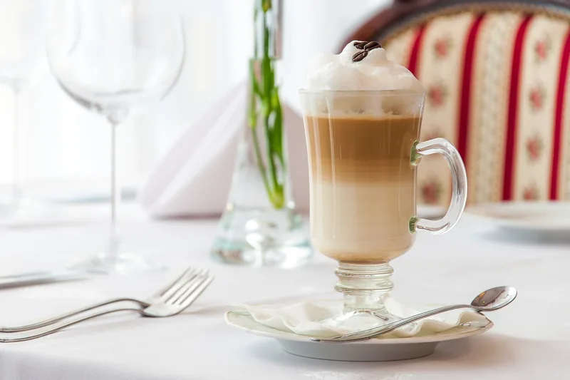 Ein einzelner, eleganter Latte Macchiato Löffel aus glänzendem Edelstahl auf hellem Grund.