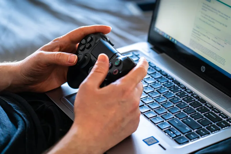 Person mit Händen auf dem Gaming-Laptop, intensiv in ein Spiel vertieft, spannende Szene.
