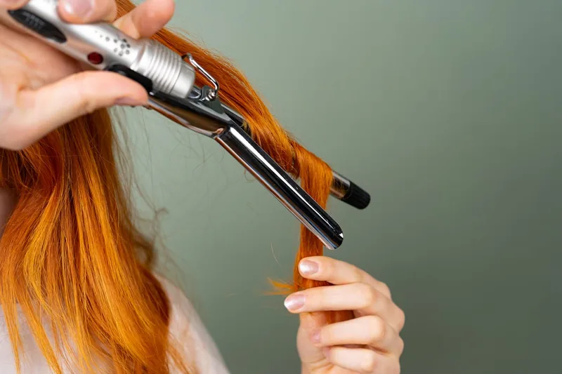 Eine Person stylt mit einem Lockenstab ohne Klemme ihr Haar und erzeugt sanfte Wellen.