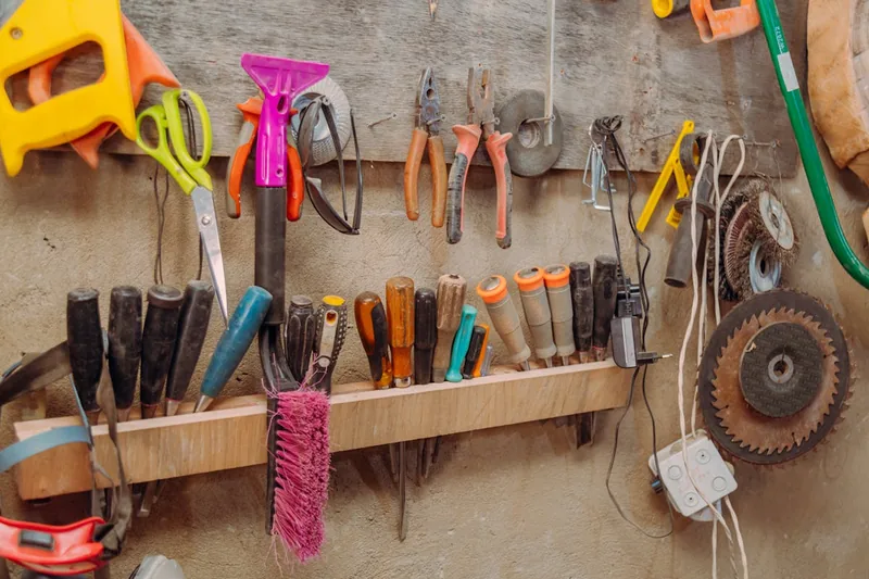 Aufgeräumter Werkstattbereich mit Werkzeugen und fertigem Holzprojekt im Hintergrund.