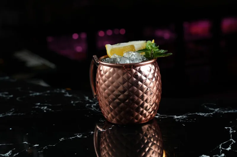 Eine Hand hält einen gefüllten Moscow-Mule-Becher mit Eis und Limette, bereit zum Genießen.