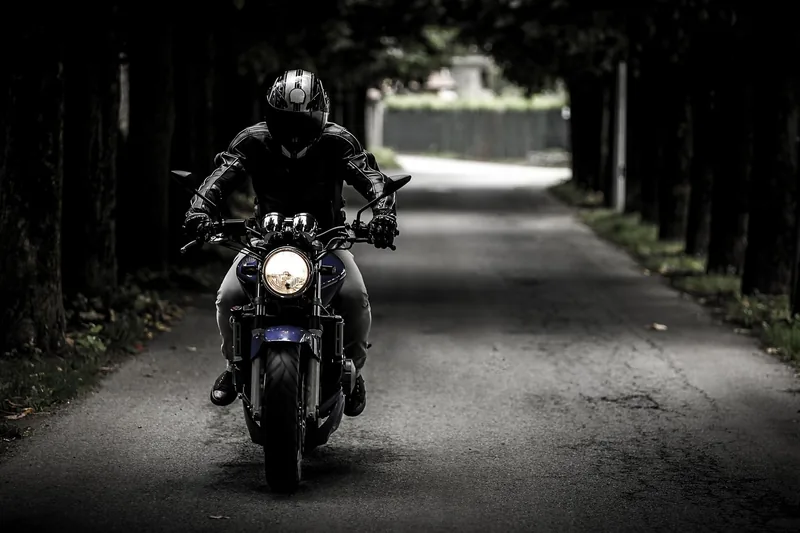 Ein Motorradfahrer trägt eine Beintasche während der Fahrt auf einer kurvigen Landstraße.