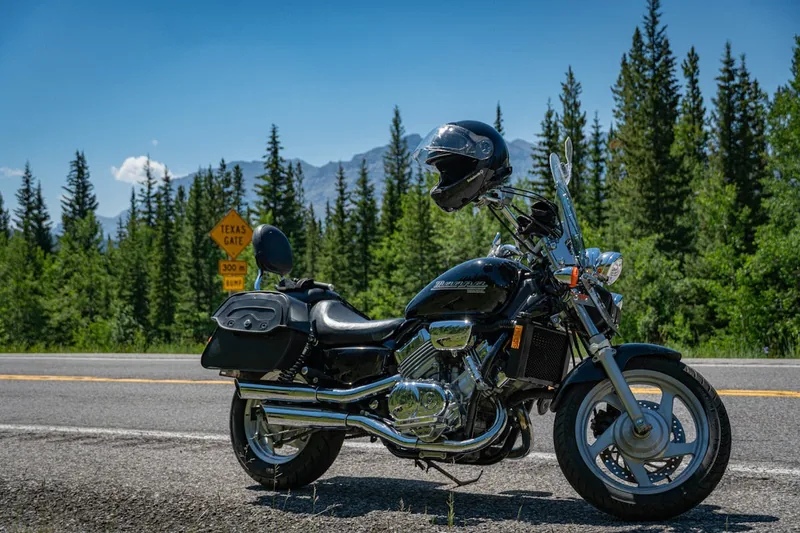 Ein Motorrad steht an einem Aussichtspunkt mit Alpenpanorama, symbolisierend Freiheit und Reisekomfort.
