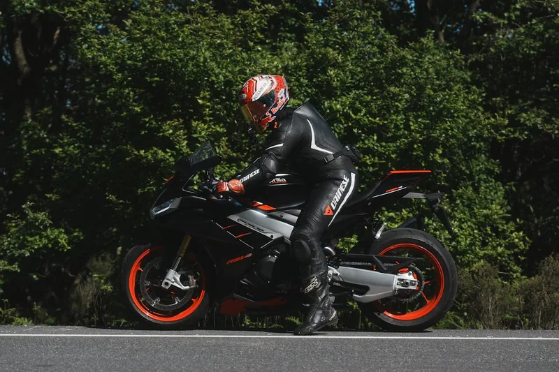 Ein Motorradfahrer in voller Lederkombi sitzt auf einem Motorrad und blickt bereitwillig in die Ferne.