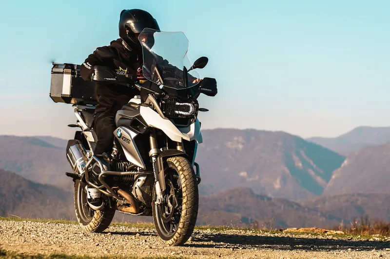 Ein Motorradfahrer auf Tour, im Hintergrund eine malerische Landschaft, unterstreicht die Wichtigkeit sicherer Ausrüstung.