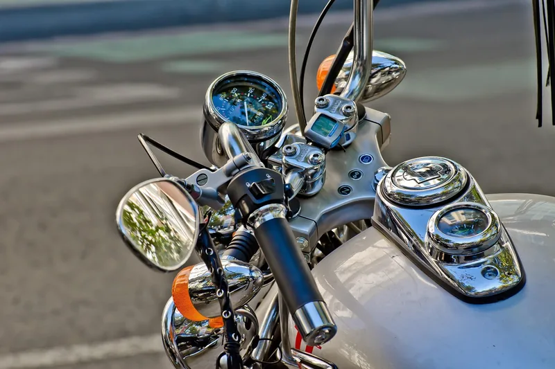 Eine Hand mit einem Motorradhandschuh greift den Lenker eines Motorrads vor dem Start.