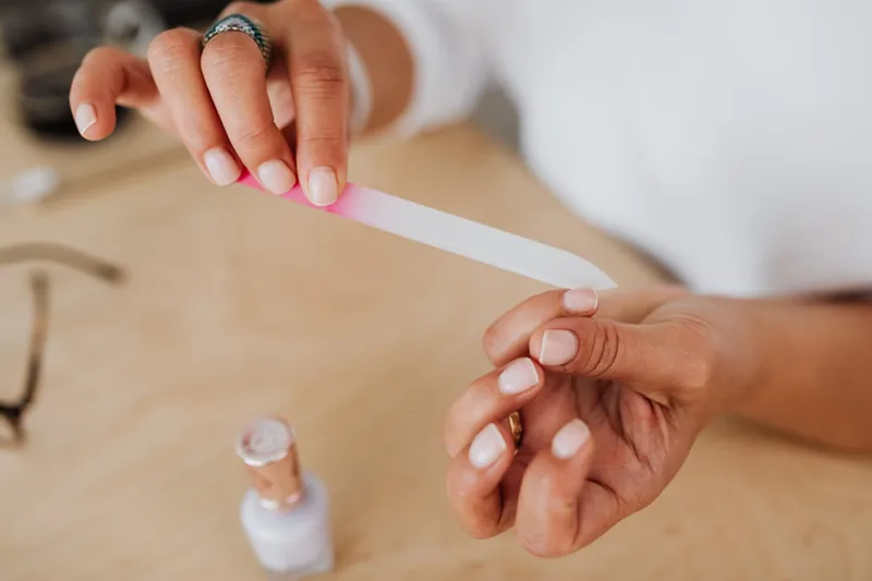 Eine Person benutzt eine Nagelfeile aus dem Nageletui zur präzisen Pflege ihrer Fingernägel.