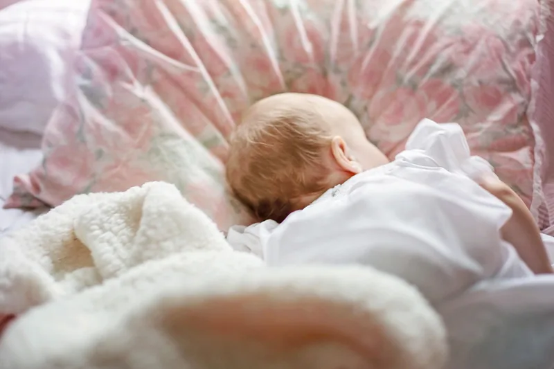 Ein friedlich schlafendes Baby in seinem Bettchen, das dank freier Atemwege ruhig atmet.