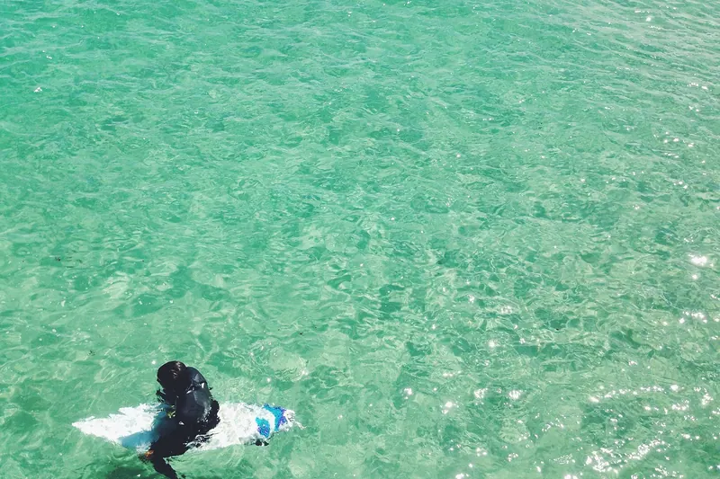 Person in Neoprenanzug beim Surfen, bereit für die Wellen und Wassersporterlebnisse.