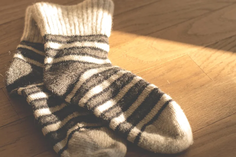 Eine Person trägt gemütliche Norweger-Socken beim Entspannen zu Hause, die Füße auf einem weichen Teppich.